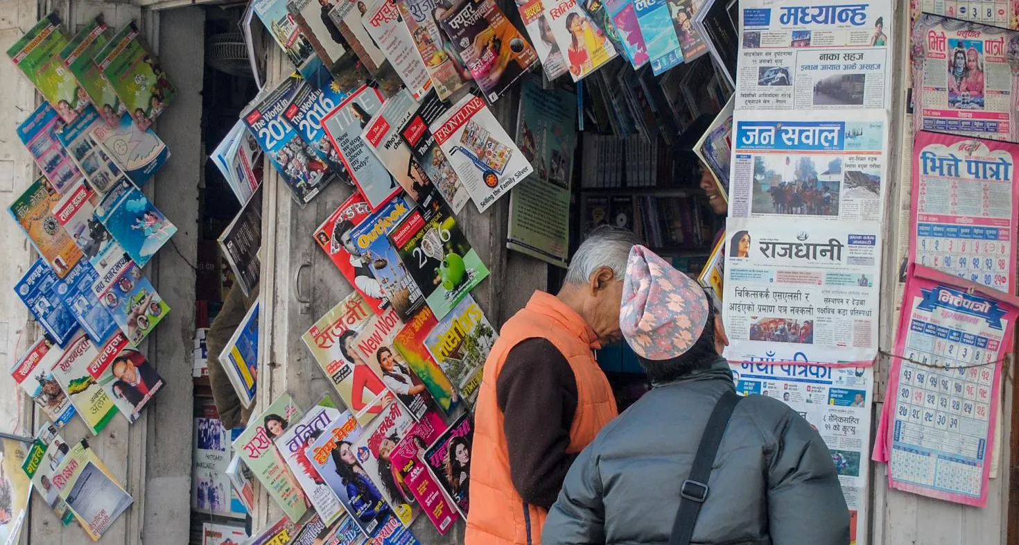 Man standing in front of newspaper stand.