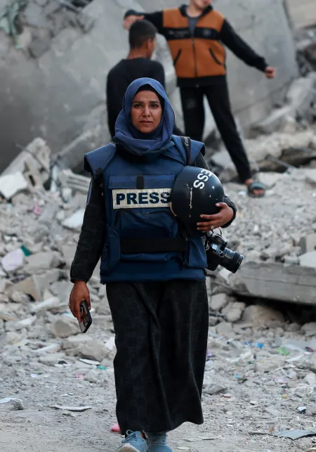 Journalist tegenover een achtergrond van puin.