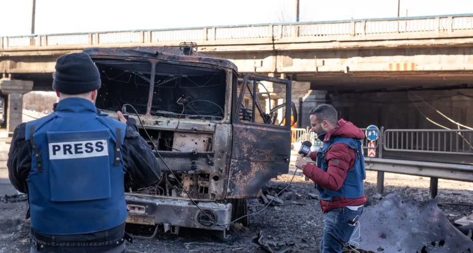 Kyiv, Ukraine - 02.28.2022: The war is between Russia and Ukraine. an Israeli film crew filming a report in Kyiv n Pobedy Avenue near a burned-out truck