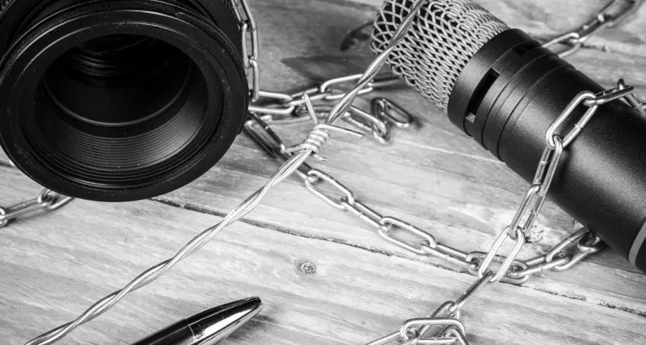 A balck and white photo where a camera, a microphone and a pen are chained